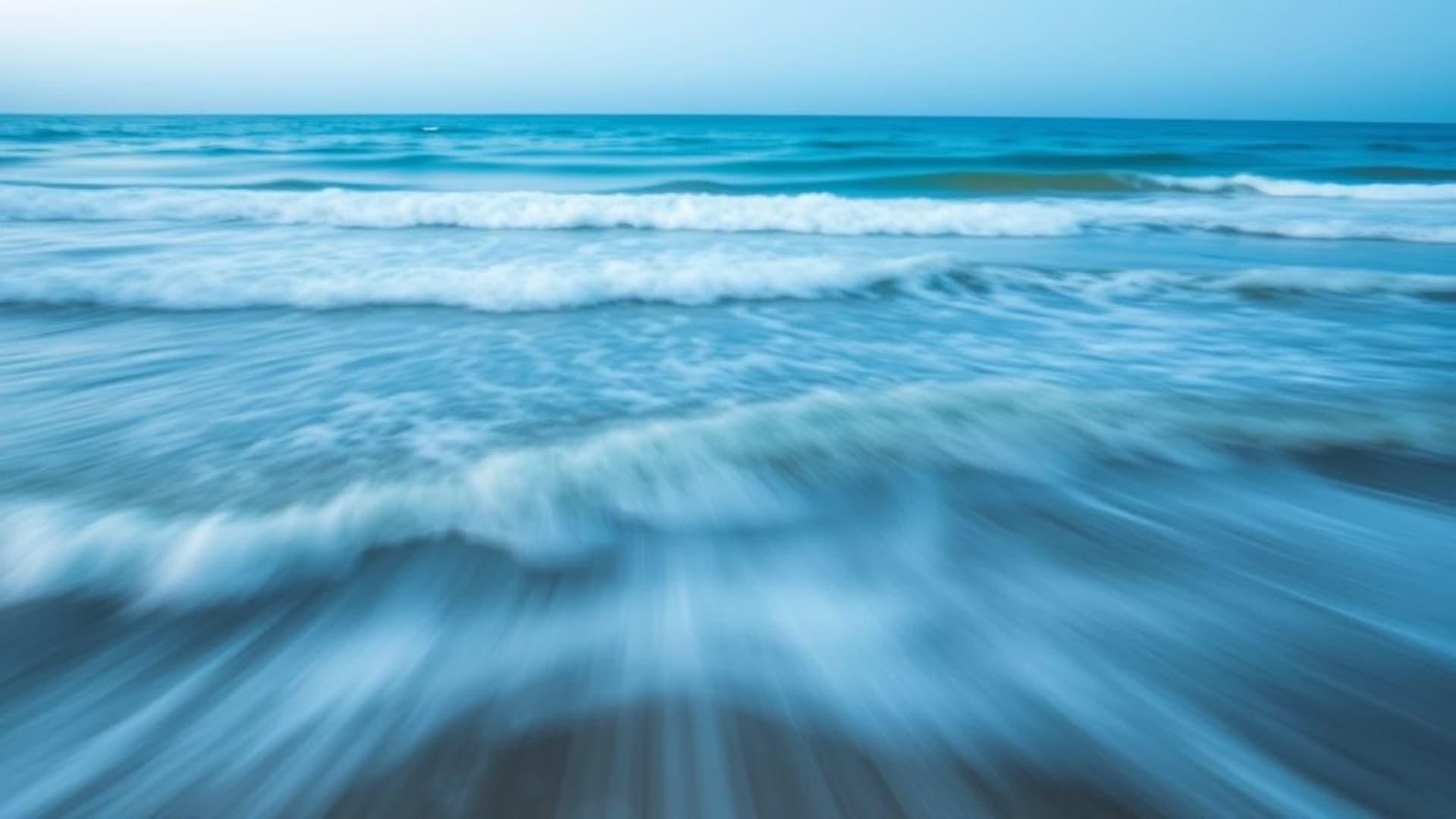 Vagues océaniques en pose longue avec flou d'arrière-plan, embruns de mer, horizon dégradé bleu, fond d'écran apaisant, mouvement tranquille